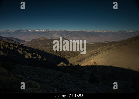 Giugno 14, 2014 - White Mountains, California, Stati Uniti - Montagne della Sierra Nevada e il Monte Whitney visto al sorgere e calare della luna da montagne bianche attraverso Owens Valley. Sotto il profilo ecologico, le montagne bianche sono come le altre gamme nel bacino e la gamma provincia; sono asciutti, ma i pendii superiore da 9.200 a 11.500 ft tenere aperte le foreste subalpine del Grande Bacino bristlecone pine. Un pino bristlecone è una delle tre specie di alberi di pino (Famiglia Pinaceae, genere Pinus, sottosezione Balfourianae). Tutte e tre le specie sono di lunga durata e altamente resistenti a condizioni climatiche avverse e terreni sconnessi. Uno dei t Foto Stock