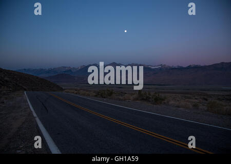 Giugno 14, 2014 - White Mountains, California, Stati Uniti - Autostrada 168 e sulle montagne di Sierra Nevada con il Monte Whitney visto al sorgere e calare della luna da montagne bianche attraverso Owens Valley. Sotto il profilo ecologico, le montagne bianche sono come le altre gamme nel bacino e la gamma provincia; sono asciutti, ma i pendii superiore da 9.200 a 11.500 ft tenere aperte le foreste subalpine del Grande Bacino bristlecone pine. Un pino bristlecone è una delle tre specie di alberi di pino (Famiglia Pinaceae, genere Pinus, sottosezione Balfourianae). Tutte e tre le specie sono di lunga durata e altamente resistenti a condizioni climatiche avverse e cattivo così Foto Stock