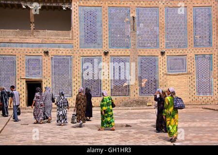 Donne uzbeke passeggiate nel cortile del Tosh Hovli palace di Khiva, Uzbekistan Foto Stock