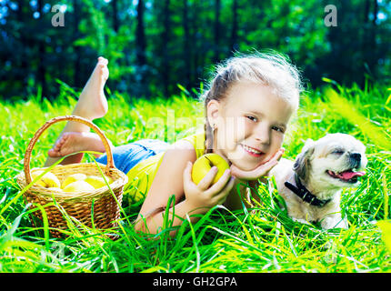 Felice ragazza avente un pic-nic con il suo cane in estate park Foto Stock