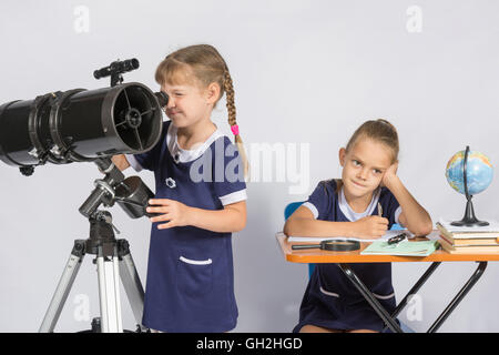 Astronomo ragazza guarda attraverso l'oculare del telescopio, l'altra ragazza pensando di attesa per i risultati delle osservazioni Foto Stock