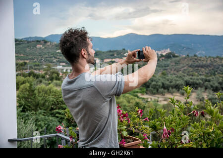 Bel giovane uomo prendendo foto con il telefono cellulare del paesaggio Foto Stock