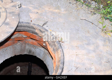 Cesspit in cemento con una botola aperta sul terreno in estate. Foto Stock