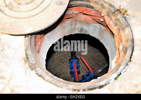 Cesspit in cemento con una botola aperta sul terreno in estate. Foto Stock