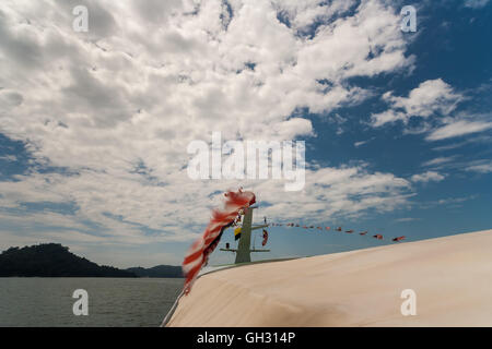 Gita in barca sul Borneo Malese. Le bandiere sono sbattimenti nel vento. Foto Stock