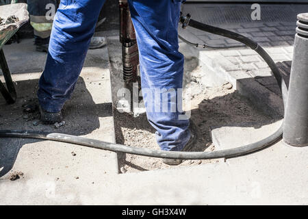 Builder lavoratore con martello pneumatico attrezzatura di perforazione rottura asfalto marciapiede sulla strada Foto Stock