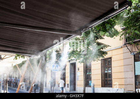 Tendaggio sprinkler gli spruzzi di acqua nebulizzata al bar sulla terrazza al fine di raffreddare la calda estate la temperatura in Spagna Foto Stock