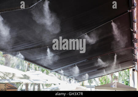 Tendaggio sprinkler gli spruzzi di acqua nebulizzata al bar sulla terrazza al fine di raffreddare la calda estate la temperatura in Spagna Foto Stock