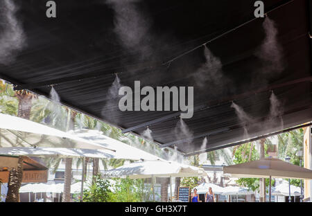 Tendaggio sprinkler gli spruzzi di acqua nebulizzata al bar sulla terrazza al fine di raffreddare la calda estate la temperatura in Spagna Foto Stock