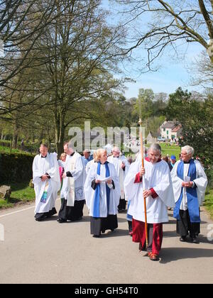 I membri del clero e processo di visitatori a benedire la ben medicazioni a Tissington, Derbyshire, Regno Unito Foto Stock