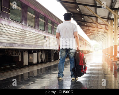 Asian traveler uomo con beni in attesa per i viaggi in treno a Chiang Mai stazione ferroviaria, Thailandia. Foto Stock