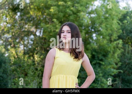 Teen girl in abito giallo in piedi nel parco Foto Stock