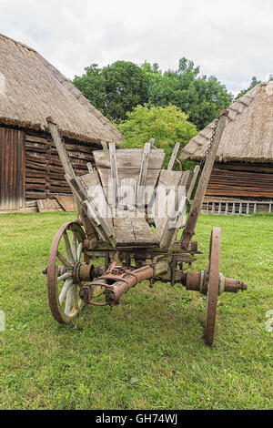 Antica storia grunge carro rustico, paese vecchio agricoltura tradizionale case come sfondo. Foto Stock