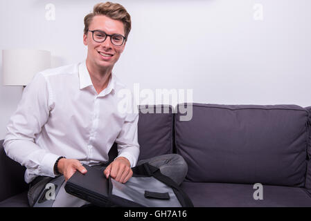 Sorridente giovane uomo d affari imballaggio della sua borsa sul lettino Foto Stock