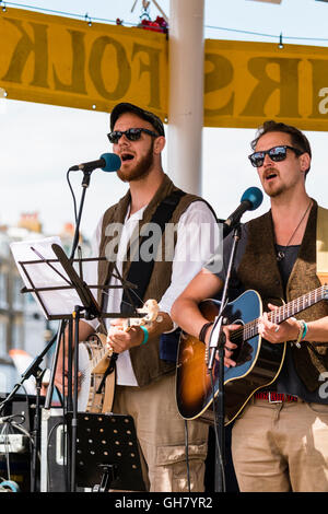 Broadstairs settimana della musica folk festival. Giovani cantanti folk indossando occhiali da sole scuri, una riproduzione di banjo, l'altra chitarra, eseguire all'aperto nel palco per spettacoli. Close-up. Foto Stock