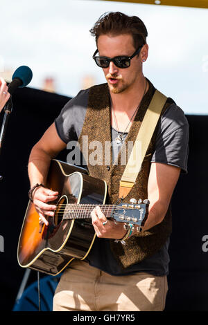 Broadstairs settimana della musica folk. Giovane cantante folk chitarrista, indossando occhiali da sole scuri, eseguendo in bandstand. Close up della cantante e chitarra. Foto Stock