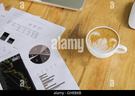 I documenti aziendali con i grafici di crescita e caffè. imprenditore sul posto di lavoro Foto Stock