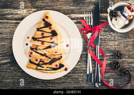 Albero di natale a forma di frittelle dolci sul tavolo di legno per la colazione, tratta, vista dall'alto, toni rétro Foto Stock