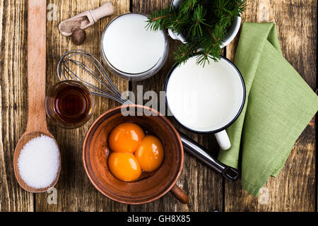 Zabaione ingredienti su tavola in legno rustico visto dal di sopra. Uovo punzone di latte a crudo con i tuorli, il latte, la crema di latte, zucchero, bourbon Foto Stock