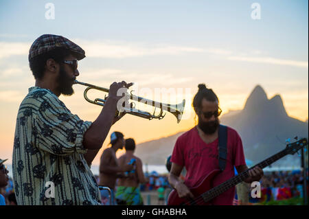 RIO DE JANEIRO - Febbraio 21, 2015: Silhouette di un musicista di suonare il clacson per un pubblico presso la popolare Arpoador sunset spot Foto Stock