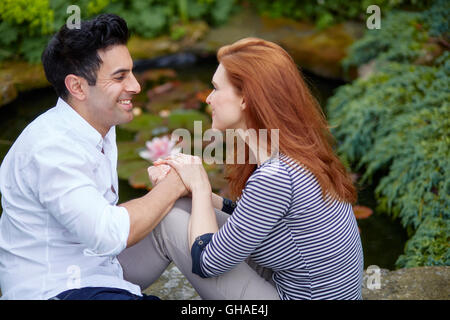 Amare giovane seduto fuori in giardino Foto Stock