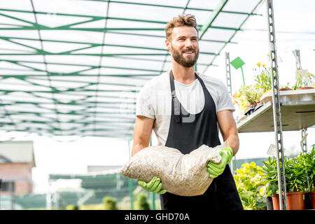 Bello il giardiniere con la sacca di suolo Foto Stock