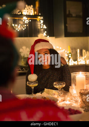 Donna sorridente indossando Santa hat a lume di candela la cena di Natale party Foto Stock