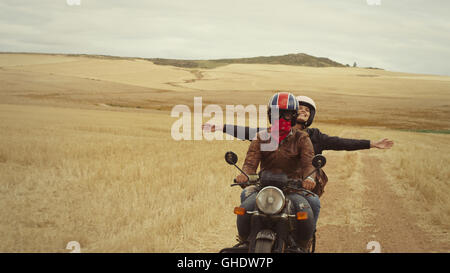 Esuberante giovane donna in sella moto nel paesaggio rurale Foto Stock
