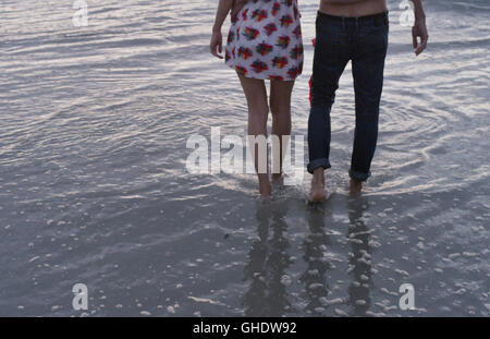 Coppia giovane camminando in ocean surf Foto Stock