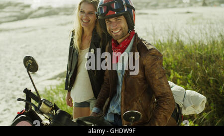 Ritratto sorridente coppia giovane in motocicletta sulla spiaggia Foto Stock