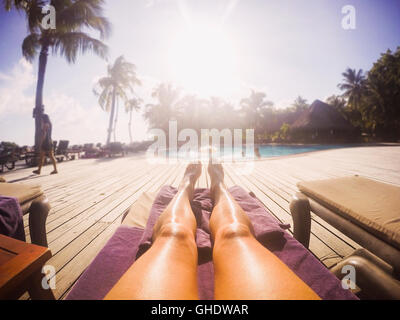 La donna a prendere il sole al sole a bordo piscina tropicale Foto Stock