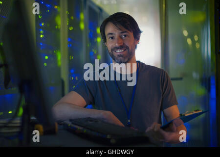 Ritratto sorridente sala server tecnico con appunti al computer Foto Stock
