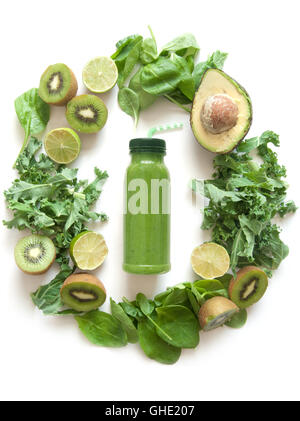 Imbottigliato frullato verde circondato con frutta e verdura compresi gli spinaci kale e avocado Foto Stock