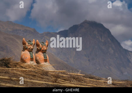 Due mucca che assomiglia in porcellana Statuette inca sul tetto della capanna del villaggio Foto Stock