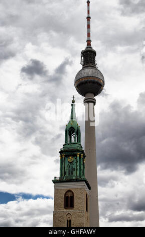 Vista del campanile di una chiesa di fronte la torre della televisione con sfondo nuvoloso Foto Stock