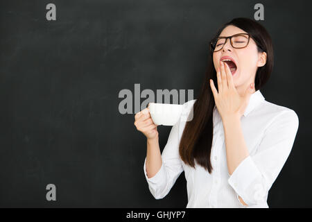 Un buon insegnante asiatici sente assonnato e di bere il caffè nella scuola Foto Stock