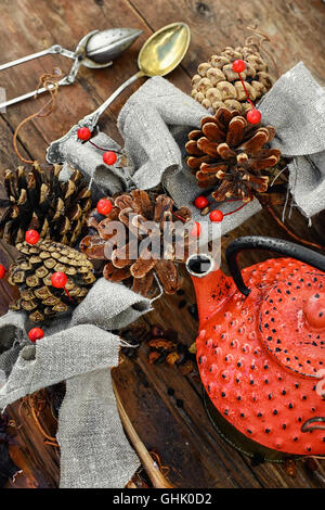 Rosso teiera in metallo,le foglie di tè e autunno pigne Foto Stock