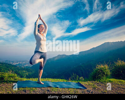 Donna fare yoga asana Vrikshasana tree pongono in montagna all'aperto Foto Stock