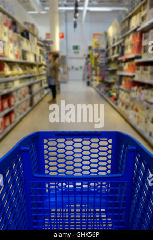 Carrello acquisti in un supermercato con ripiani sfocata in background Foto Stock
