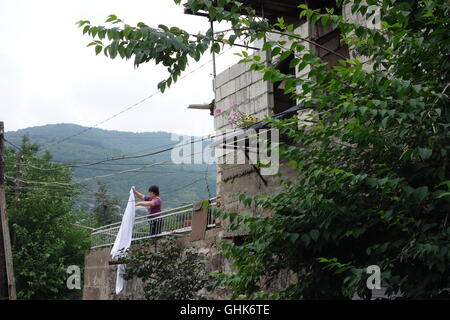 Goris Armenia città in montagna donna di stendere la biancheria sul balcone della metà costruita casa estensione Foto Stock