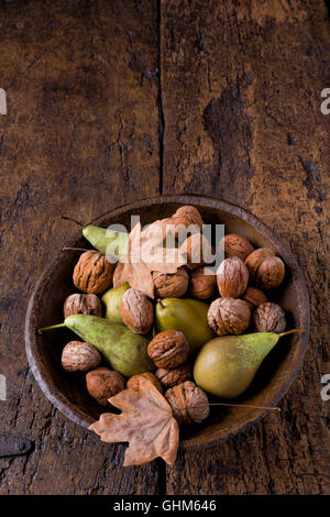 Rientrano ancora in vita con una ciotola di pere e noci su un grunge sfondo di legno Foto Stock