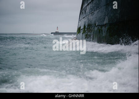 Tempesta stagionale che mostra la parete del porto di Fraserburgh e il faro in cattive condizioni atmosferiche con le onde che si infrangono. Foto Stock