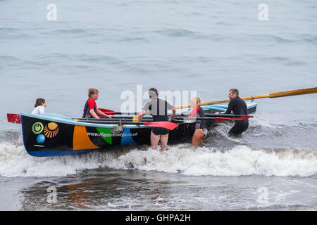 Un team di canottaggio con un gig barca sulla spiaggia di Trevaunance Cove, Sant Agnese, Cornwall, England, Regno Unito Foto Stock