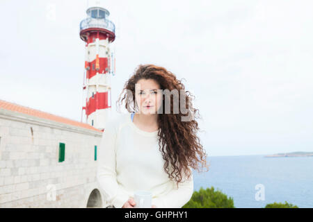 Giovane donna si prende una pausa con il faro in background Foto Stock