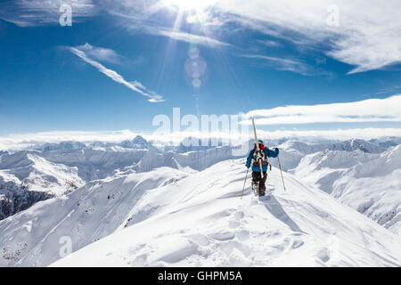 Junger Skitourengeher / con rifiniture am Gipfelgrat auf der Suche nach der Abfahrt besten Foto Stock