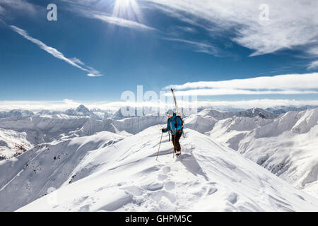 Junger Skitourengeher / con rifiniture am Gipfelgrat auf der Suche nach der Abfahrt besten Foto Stock