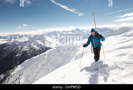 Junger Skitourengeher / con rifiniture am Gipfelgrat auf der Suche nach der Abfahrt besten Foto Stock