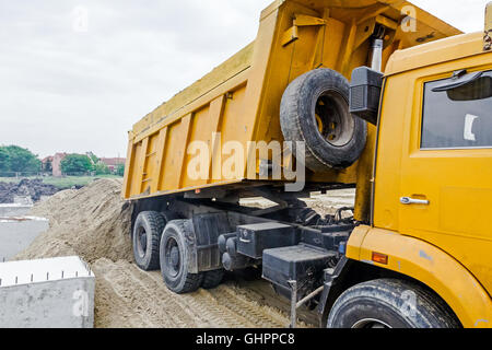 Dumper è lo scarico nel suolo o sabbia al sito in costruzione. Il paesaggio si trasformano in area urbana. Foto Stock