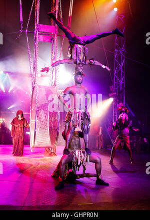 Circus degli orrori cast: Il keniota guerrieri Troupe acrobatica nelle prestazioni con anello Dr master Haze in background sulla posizione nella big top. Foto Stock