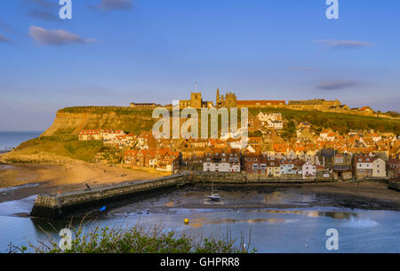 Whitby Harbour e pittoresche rovine di Whitby Abbey sulla East Cliff al tramonto Foto Stock